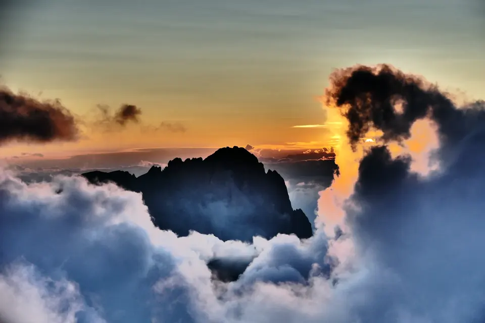 Una vetta emerge dalle nuvole nella luce calda del tramonto